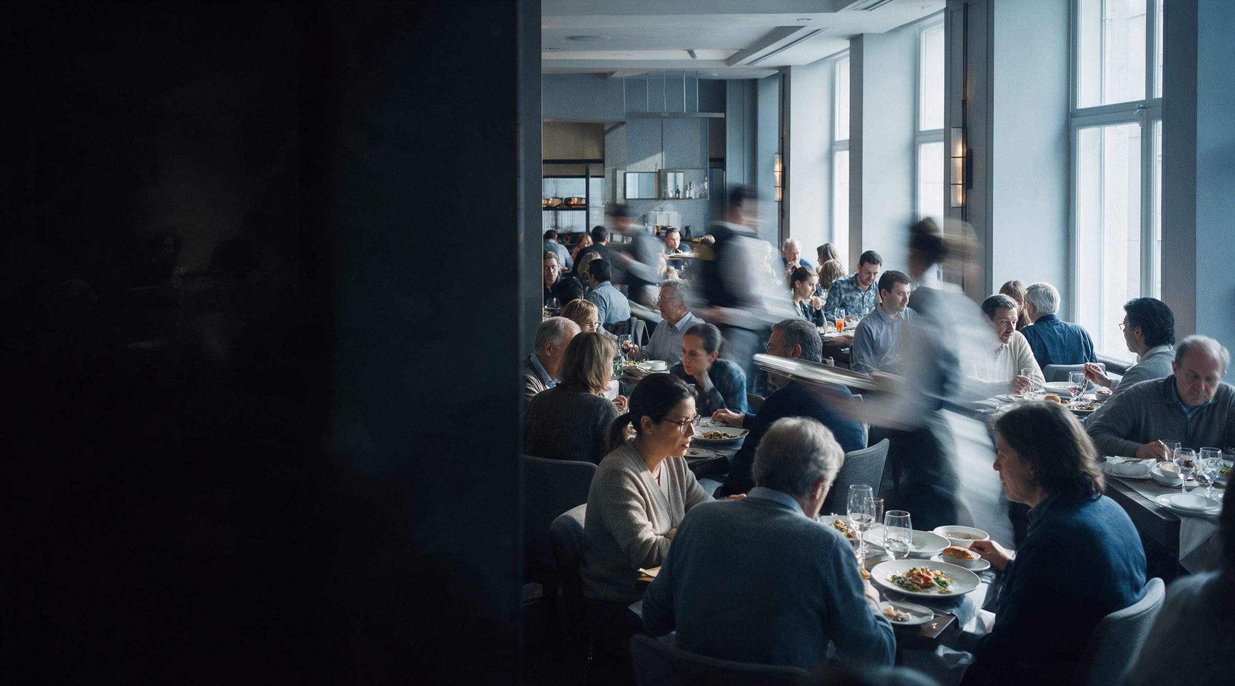 Comedor de restaurante a mediodía, mesas llenas y garzones en movimiento.